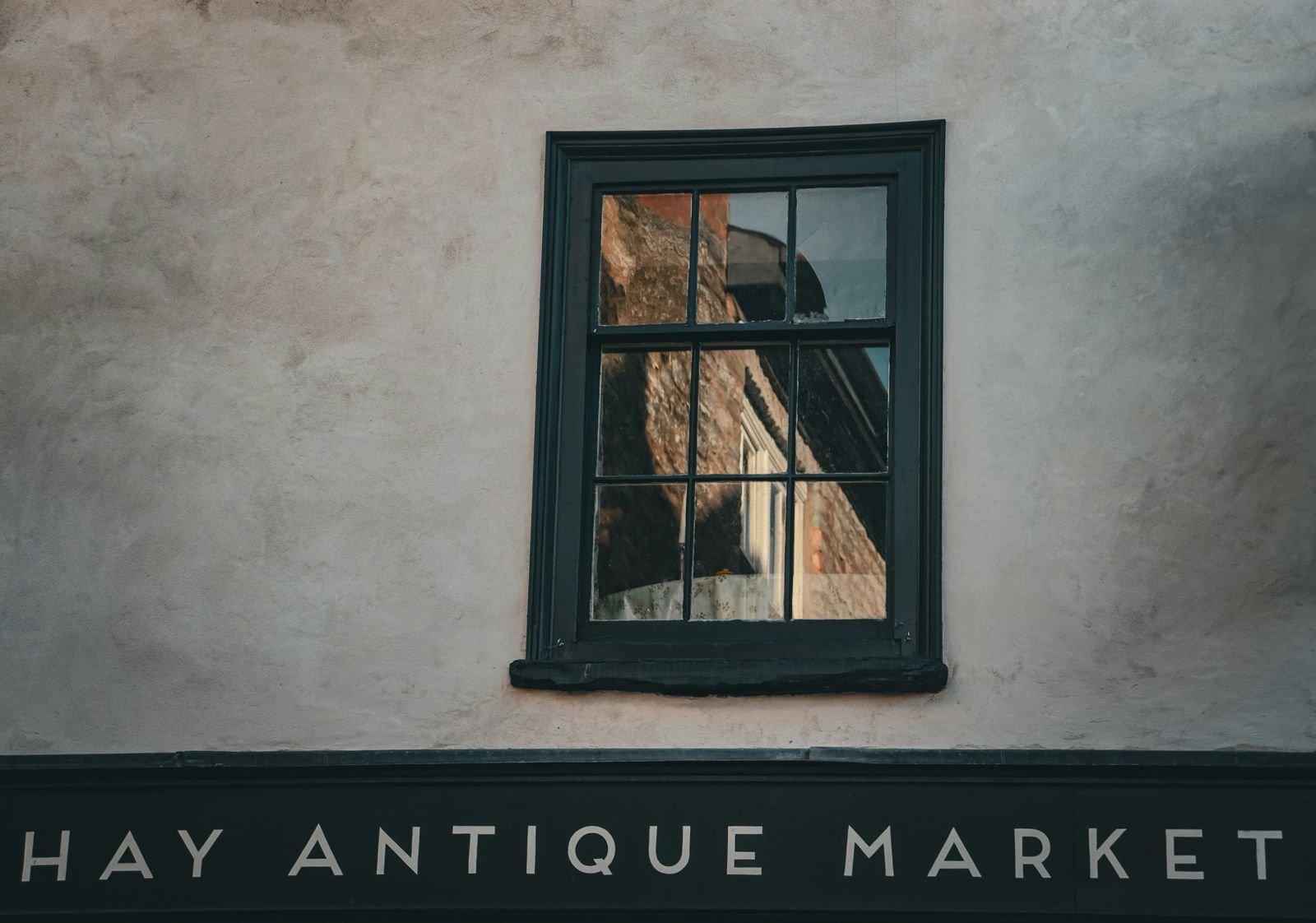 A sash window above the painted sign of Hay Antique Market in Hay-on-Wye