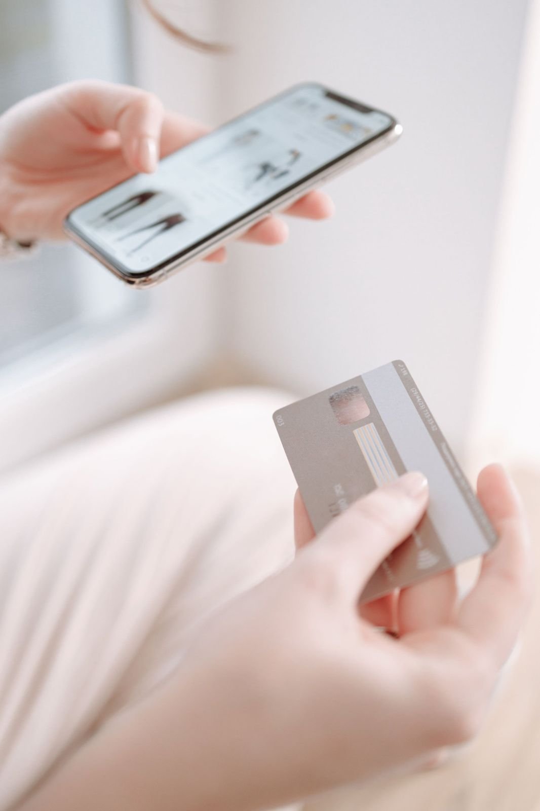Someone booking on a phone with a payment card in their other hand