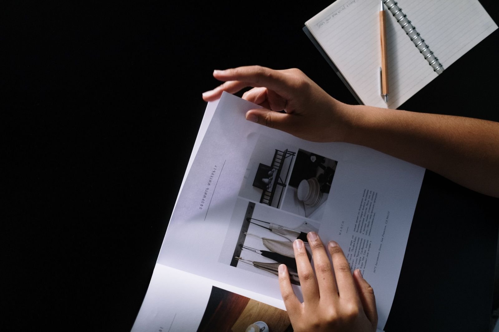 Hands turning the pages of a printed brochure full of photographs